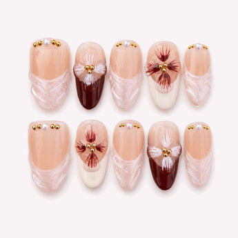 Fleur de Bordeaux burgundy press on nails with French tip curves, painted floral details, gold beads and pearl-like accents.