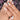 Jardin Pastel short almond 3D flower nails worn on a hand with pastel blue and yellow details and raised floral accents.