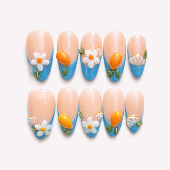 Capri Escape blue French tip nails with flowers, a nude-blush base, sculptural citrus accents, green leaves and a medium almond shape.