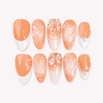 Veiled Vow wedding press-on nails with a nude-pink base, pearl-like bead accents, clear sculptural 3D bows, white French and V-tip details, and a medium almond shape.