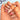 Seashell Garden 3D shell nails worn on a hand in a medium almond shape with a nude-pink base, sculptural pink shell relief, white floral details and red accents.
