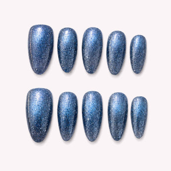 Silver Stardust silver cat eye nails with an icy blue silver finish, fine glitter, charcoal-to-black shading, luminous cat-eye light bands and a medium almond shape.