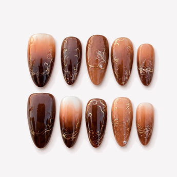Vintage Cafe brown ombre nails with deep espresso-brown, nude beige, ivory and caramel tonal transitions, gold-tone botanical line art, subtle glitter accents and a medium almond shape.