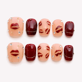 Burgundy Kiss cute Valentine nails with burgundy color, raised kiss motifs and crystal-like accents.