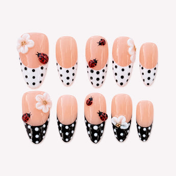 Dot & Daisy Garden polka dot French tip nails with 3D ladybugs, white flowers and a peach-nude almond shape.