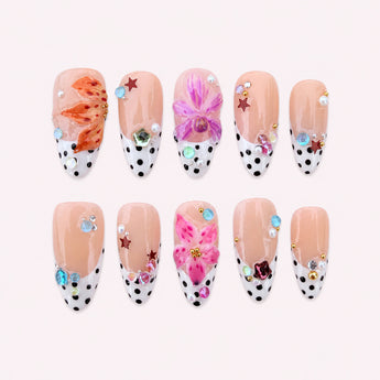 Bloom Dot Reverie black and white polka dot nails with colorful raised flowers and jewel-like accents.