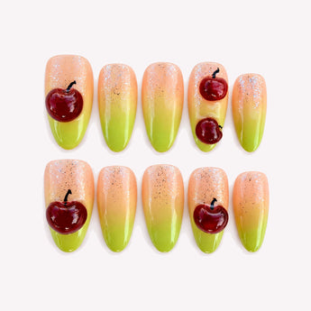 Cherry Wink press-on nails with raised wine-red cherries, a pink-to-lime-green fade and fine sparkle.