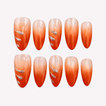 Ember Drift orange ombre press-on nails with a nude base, glossy finish and silver-tone swoosh accents.