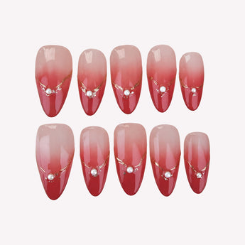 Love Token nails with a glossy nude-to-rose-red fade, gold-tone arcs and white pearl-like beads, shown in short almond.