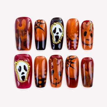 Last Laugh square Halloween press-on nails with amber brown tones, white fright masks, and raised gold-tone bead frames.