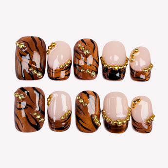 Copper Instinct brown chrome nails with tiger stripes, nude French tips, and gold-tone bead accents.