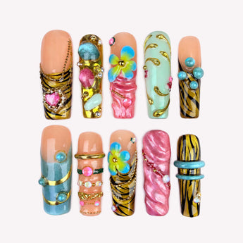 Safari Bloom press on nails with blue and yellow-green flowers, black and gold stripes, and sculptural accents.
