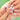 Close-up of Fleur de Bordeaux almond nails worn on hands with burgundy French tips, painted flowers and pearl-like accents.