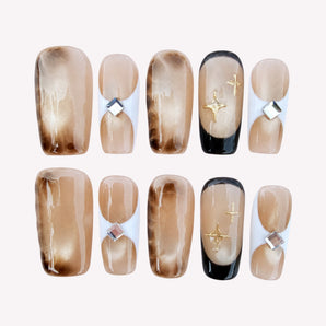 Evening Muse nude cat eye nails with smoky brown shading and gold-tone starbursts.