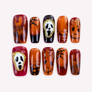 Last Laugh square Halloween press-on nails with amber brown tones, white fright masks, and raised gold-tone bead frames.